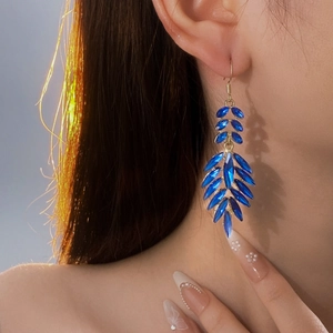 Close-up of model wearing blue crystal leaf drop earrings with gold metal accents