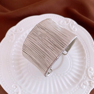 Détail d'un bracelet ouvert argenté à plusieurs fils sur une assiette blanche