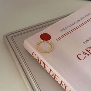 Elegant gold milgrain textured open ring in minimalist French style on a pink book