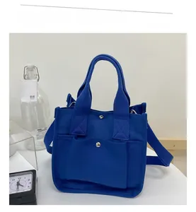 Close-up of bright blue canvas tote bag featuring front pocket and durable webbing handles