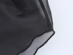 Détail du tissu en organza noir semi-transparent avec finitions de couture précises