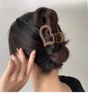 Close-up of a matte brown heart-shaped hair claw clip used for a half-up hairstyle