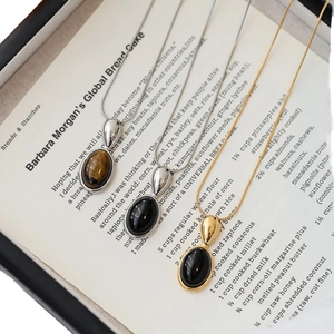 Three elegant oval resin pendant necklaces in gold and silver finish on a vintage book