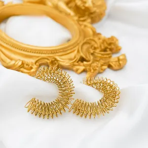 Detail of 18k gold plated stainless steel spring hoop earrings on white satin