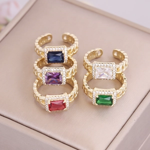 Five colorful rectangular zircon rings with gold chain bands on a jewelry box display