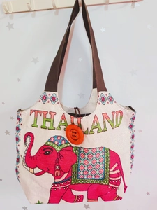 Detail der rosa Elefanten-Stickerei und Thailand-Schriftzug auf beiger Canvas-Tasche