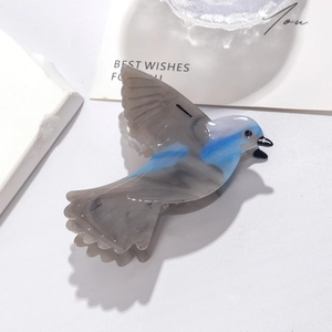 Detailed view of bird-shaped acetate hair claw with grey and blue marble texture