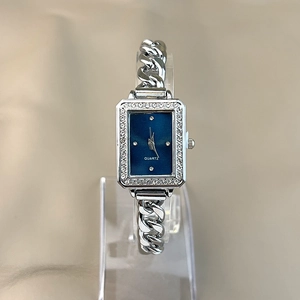 Macro view of silver bracelet watch with blue rectangular dial and rhinestone border