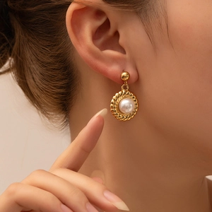 Elegant gold titanium steel earrings with retro pearls and spiral texture on a female model