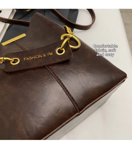 Detail of dark brown vintage leather texture with polished gold ring and chain hardware