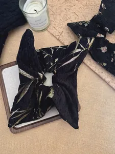 Detail of black jacquard hair scrunchie with golden bamboo leaf pattern on tray
