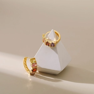 Detailed macro view of 18K gold plated hoop earrings with rainbow baguette-cut gemstones