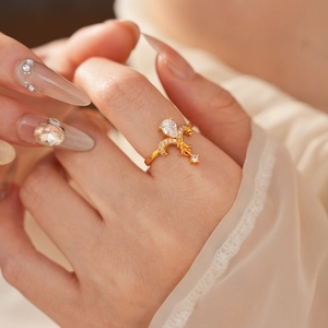 Detailed view of a vintage fleur-de-lis gold ring with teardrop zircon worn on finger
