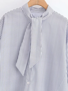 Detail of blue and white striped poplin shirt featuring a tie-up scarf neckline on a hanger