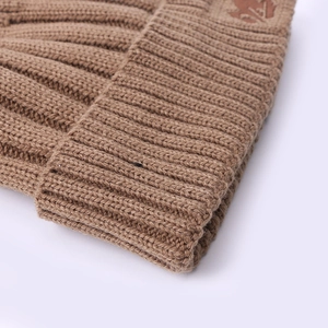 Brown knitted beanie hat with thick rib-knit texture and brown leather brand patch