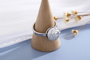 Macro view of silver floral ring with a white sphere center on a wooden stand