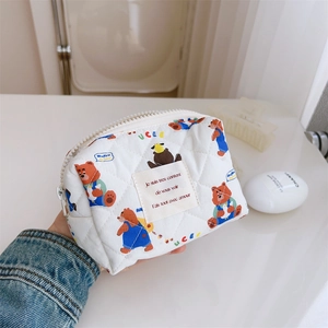 Gros plan d'une trousse à maquillage matelassée blanche avec des imprimés d'ours bruns