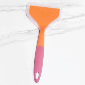 Wide silicone spatula with orange head and pink handle on marble background