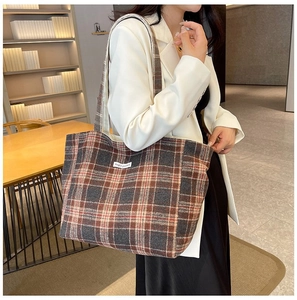 Detail view of large check pattern shoulder bag with Magic Pocket label on model