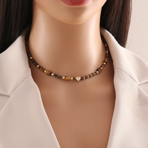 Detailed view of handmade tiger eye beaded necklace with heart pendant on a model