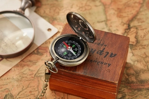 Macro view of vintage bronze compass with open cover on an old map and wood box