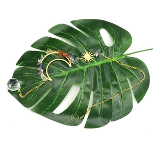 Bohemian moon and sun crystal suncatcher with natural stones on a green leaf background