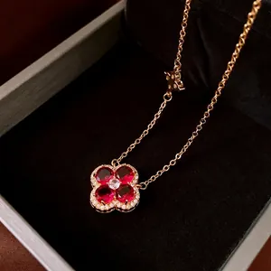 Elegant gold necklace featuring a red zircon four-leaf clover pendant on black velvet