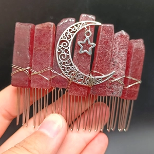 Macro detail of red crystal hair comb with silver star and crescent moon metal pendants