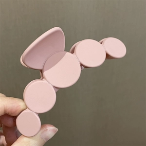 Vista de detalle de pinza para el pelo rosa mate con diseño de círculos texturizados