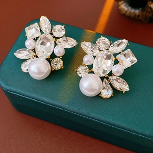 Close-up of gold-plated cluster earrings with sparkling crystals and white pearls
