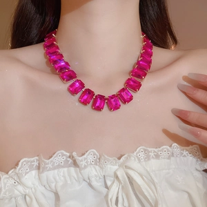 Close-up of luxury necklace featuring large fuchsia rectangular crystals set in gold