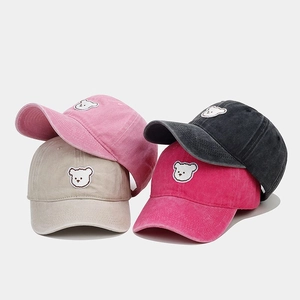 Detail of four colorful baseball caps with bear embroidery in pink, beige, and grey