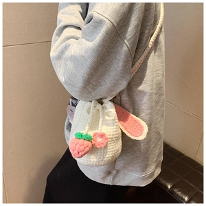 Detail of handmade crochet bucket bag featuring pink bunny ears and floral knit patterns