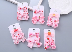 Detailed set of handmade pink ribbon hair clips for kids featuring strawberry and cherry patterns