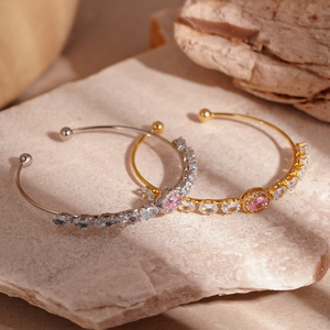Luxe open bangle with pink and blue oval gemstones on a natural stone background