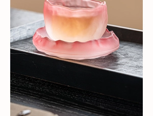 Close-up of pink frosted glass glacier teacup and matching saucer on a wood tray