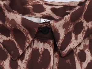 Macro view of leopard print shirt collar with black button and size S label detail