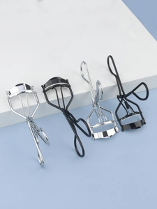 Set of four stainless steel eyelash curlers in silver and matte black on a clean blue background