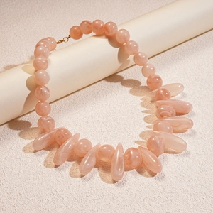 Detail view of pink acrylic marble beaded necklace with teardrop drops on display