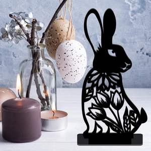 Detail of black metal Easter bunny silhouette with floral cutouts on a wooden table