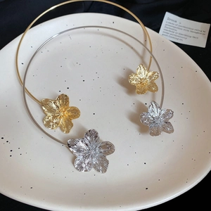Detailed close-up of gold and silver metal flower chokers with brushed texture on ceramic tray