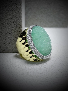 Detail of green druzy stone ring with hammered gold finish and crystal halo