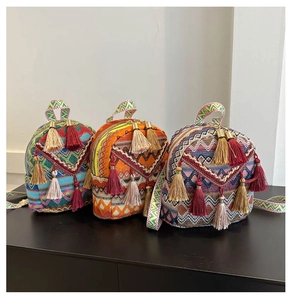 Close-up of colorful woven ethnic backpacks with bohemian tassels and diamond patterns
