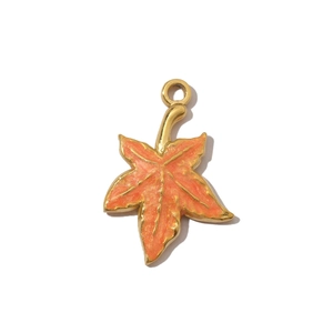 Detail of orange enamel maple leaf pendant with golden metal edges for jewelry making