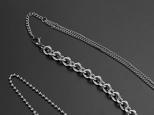 Detail of layered silver titanium steel necklace featuring curb, ring, and bead chains