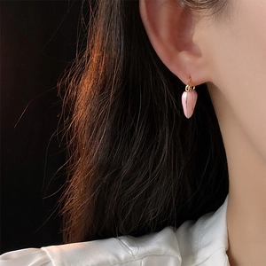 Gros plan de boucles d'oreilles fraises roses dorées sur modèle pour un style élégant