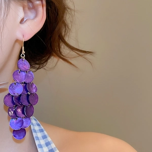 Detail of purple multilayer shell disk tassel earrings worn on ear for vacation
