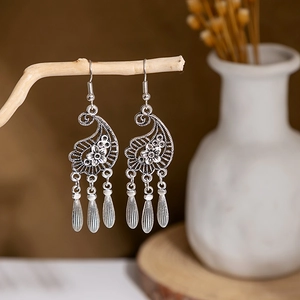 Detailed shot of bohemian silver drop earrings with floral engraving on wooden stand