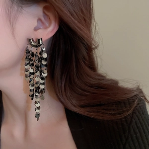 Macro detail of long fringe earrings with cascading metallic sequins in a U-shaped design