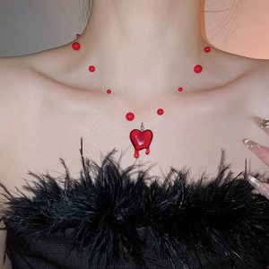 Detail of red heart pendant with melting oil drip effect on a beaded fringe necklace